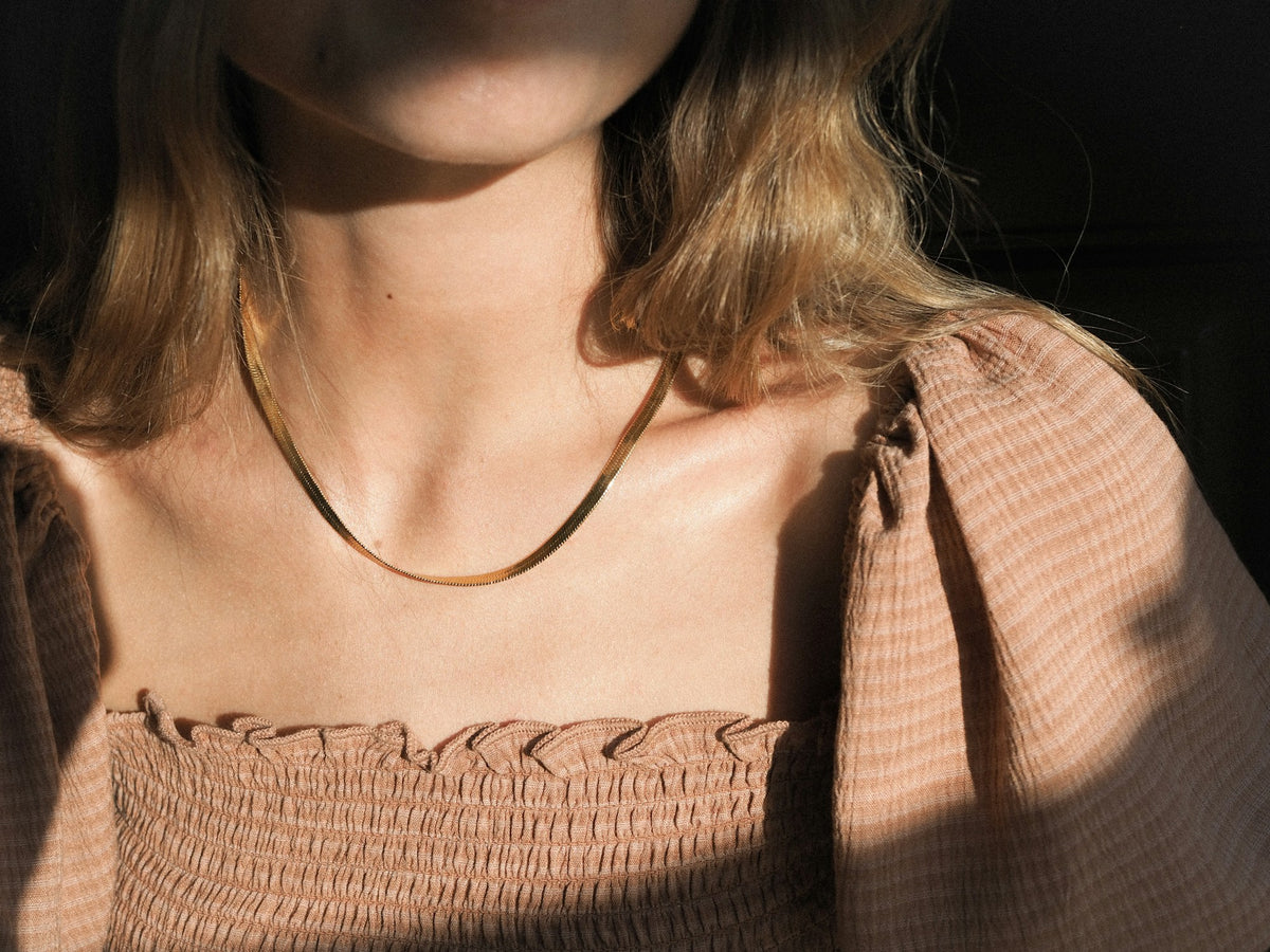 Placeholder photograph, replace before launch: a fine gold chain worn at the neck