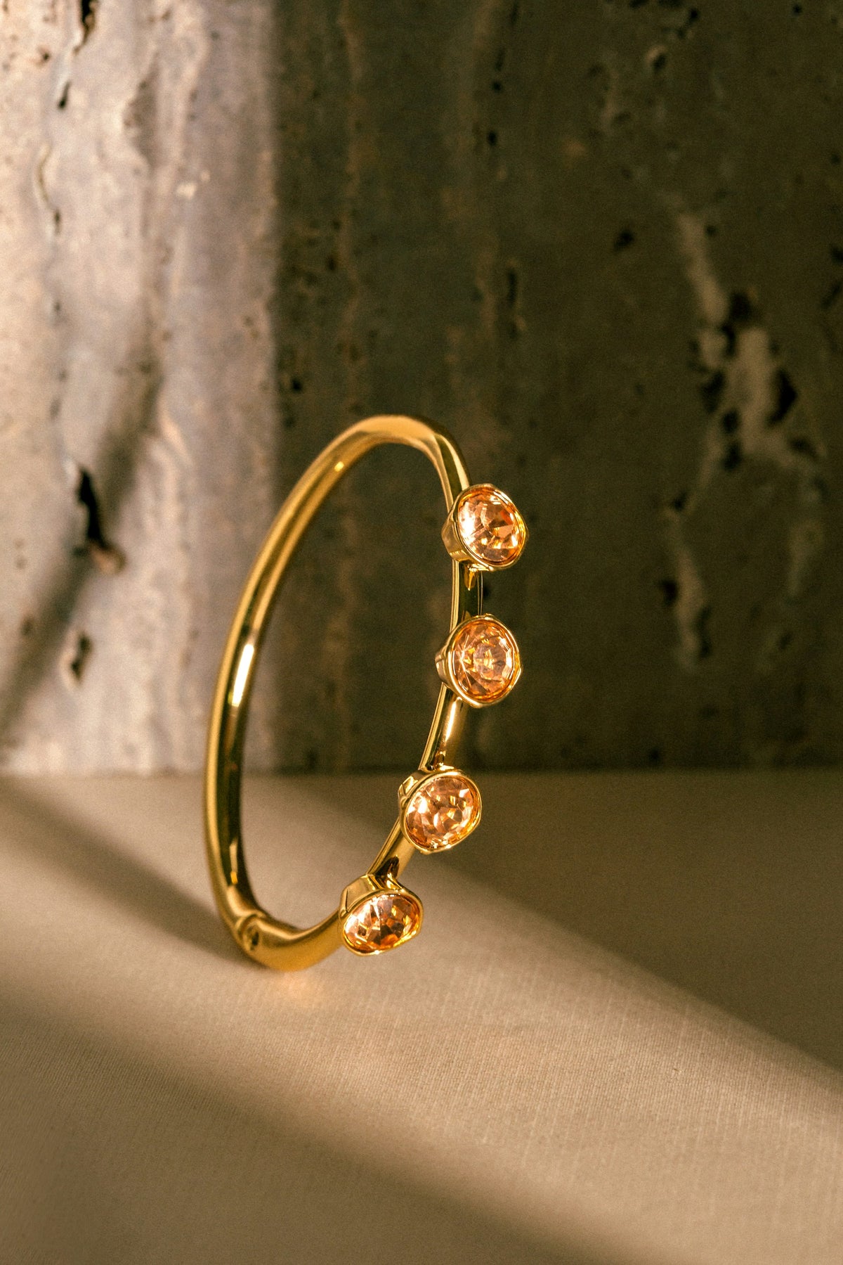 Placeholder photograph, replace before launch: a gold bangle on a warm cream surface
