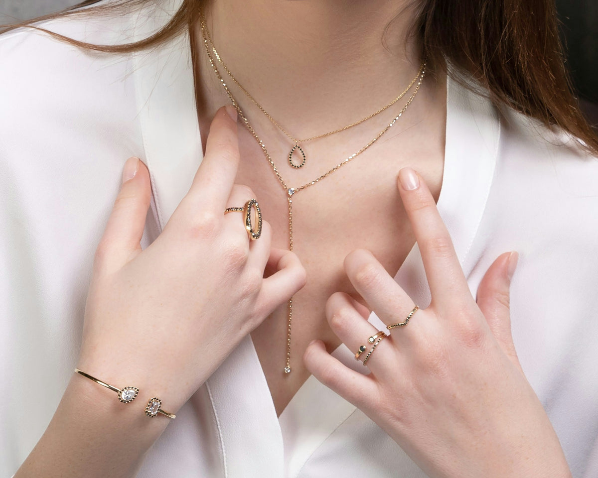 Placeholder photograph, replace before launch: layered gold necklaces and rings on a white shirt